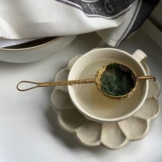 a small bowl with a spoon in it on a saucer next to a napkin