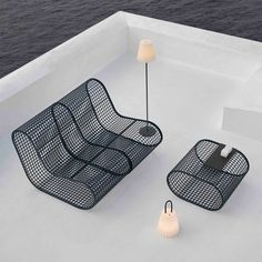 two black metal chairs sitting on top of a white roof next to lamps and water