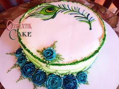 there is a cake decorated with blue roses and a peacock on it's side