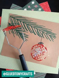 a christmas card being made with scissors and glue on top of cards that are decorated with pine needles