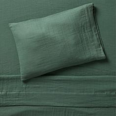 a bed with green sheets and pillows on it