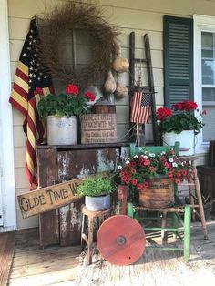 the front porch is decorated with patriotic flowers and old wooden signs, including an american flag