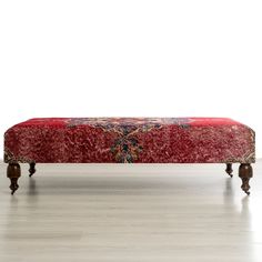 a red bench sitting on top of a hard wood floor next to a white wall