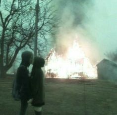 two children standing in front of a house on fire