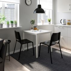 two blue chairs sitting at a white table with a clock on the wall above it