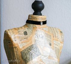 a mannequin made out of old newspapers with a black ribbon around the neck