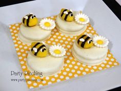 four decorated cupcakes with yellow and white frosting on a polka dot tablecloth