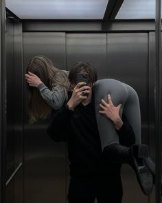 two people standing in an elevator with their arms around each other and one person taking a selfie