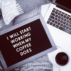 a sign that says i will start working when my coffee does on the table next to a laptop