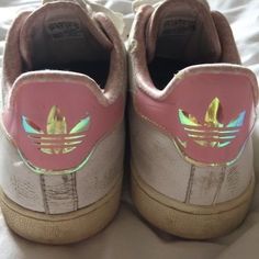 a pair of pink and gold adidas shoes on a bed with white sheets in the background