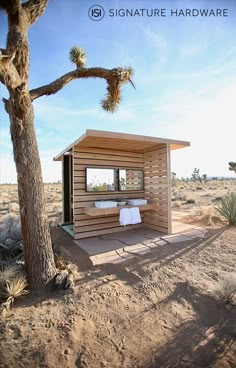 a small wooden cabin sitting in the middle of a desert with a towel on it's lap