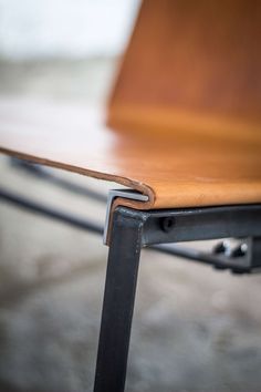 a close up view of a wooden chair with metal frame and wood seat padding