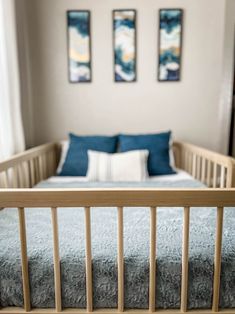 a baby crib in a bedroom with two paintings on the wall and a bed