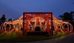 a lit up gazebo at night with lights on the sides and decorations around it