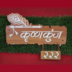 a wooden sign sitting on top of a lush green grass covered field next to a red wall