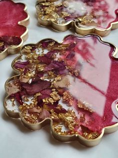 three pink and gold flower shaped trays on a white tablecloth, with one being covered in gold flakes