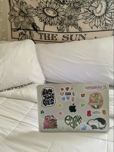 a laptop computer sitting on top of a bed covered in lots of stickers and decals