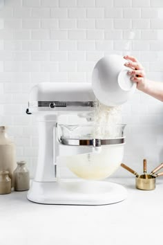 a woman is pouring batter into a mixer