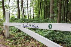 a white wooden sign sitting in the middle of a forest