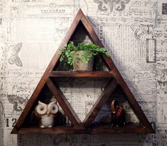 an owl figurine sits on a shelf next to a potted plant and two small owls