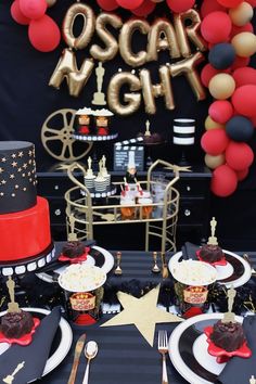 an oscar awards party with black, red and gold desserts on the table in front of balloons