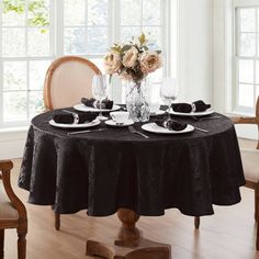 a dining room table set with black linens and place settings for two people to sit at