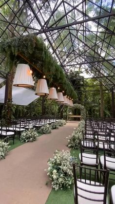 an outdoor wedding venue set up with white chairs and chandeliers hanging from the ceiling