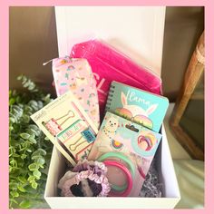 a box filled with assorted items sitting on top of a table next to a potted plant