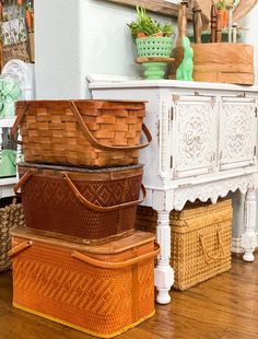 three baskets stacked on top of each other in front of a dresser and mirror with plants