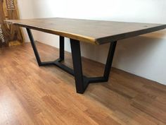 a wooden table sitting on top of a hard wood floor next to a white wall