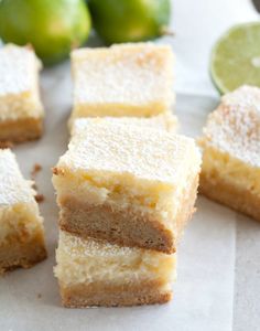 several pieces of cake with powdered sugar on top and limes in the background