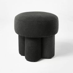 a black stool with three legs and a round foot rest on the bottom, sitting in front of a white background