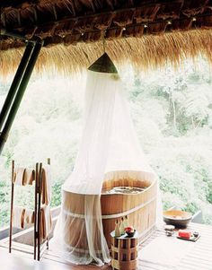 an outdoor hot tub in the middle of a room with a thatched roof over it