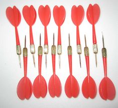 a set of nine red heart shaped toothbrushes with metal tips and gold trimmings