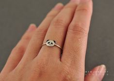 a woman's hand with a ring that has a panda face on the middle