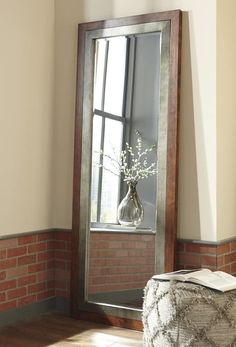 a mirror sitting on top of a wooden floor next to a window