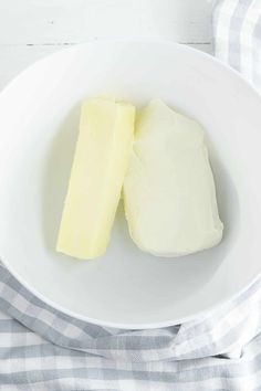 two pieces of butter in a white bowl on a blue and white checkered napkin