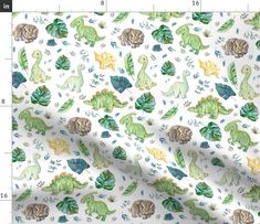 a white fabric with green dinosaurs and leaves on it, as well as a ruler