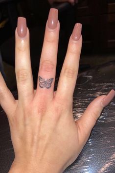 a woman's hand with a small butterfly tattoo on her left thumb and finger