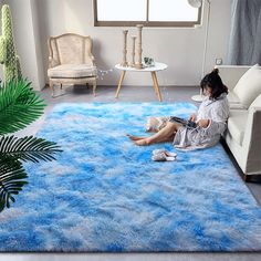 a woman sitting on the floor in front of a blue rug that looks like clouds