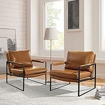 two leather chairs sitting next to each other in front of a window with a lamp