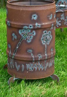 two metal planters with dandelions painted on them sitting in the grass next to each other