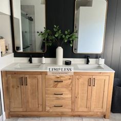 a bathroom with two sinks and mirrors on the wall next to a plant in a vase