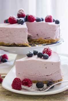 a slice of cheesecake with berries and blueberries on the top is ready to be eaten