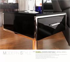 the modern side table is black with chrome trimmings and has a wine glass on it