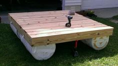 a wooden table sitting on wheels in the grass