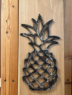 a metal pineapple hanging on a wooden wall