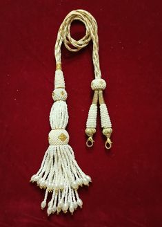 a white tassel on a red background with gold trimmings and two other tassels