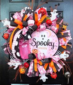 a pink and black halloween wreath on a door with spooky season written on it