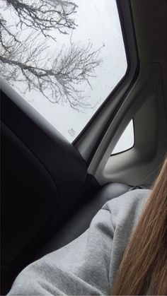 a woman sitting in the driver's seat of a car looking out the window